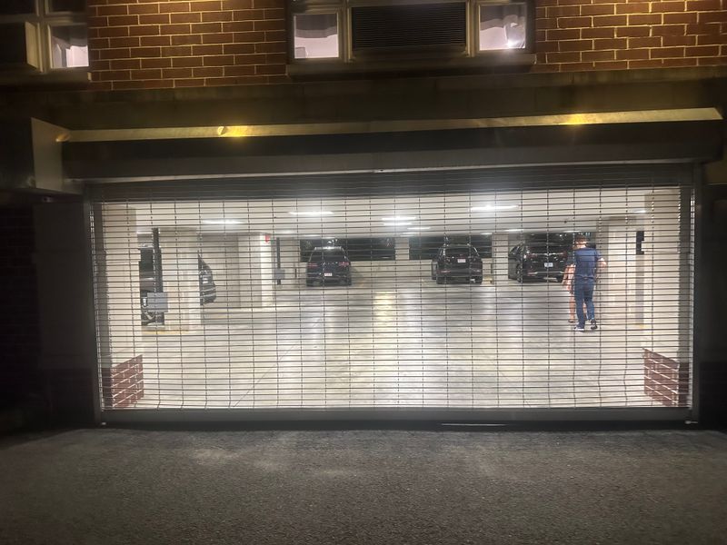 Parking garage security grille door at night with vehicles visible inside
